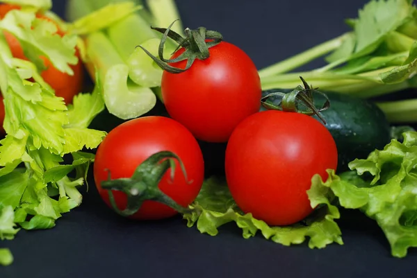 Yakın üç taze, organik kırmızı domates bir kara tahta, bulanık salatalık ve maydanoz içinde belgili tanımlık geçmiş.