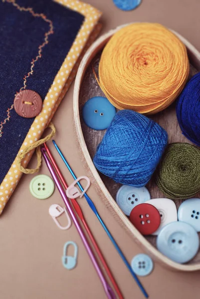 Színes Knitting tekercs nincs fonalak és horgolt eszközök bézs háttér gombokkal. Függőleges kép. Kézzel készített eszközök, kellékek, hobbi — Stock Fotó