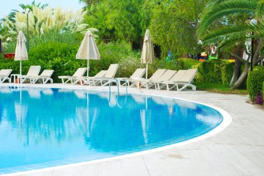 Şemsiye ve sandalyeler ile güzel lüks otel Yüzme Havuzu tesisi. Türkiye, yan. Yaz tatili.