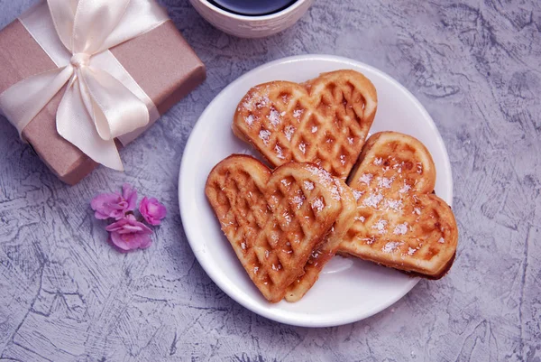 Waffeln in cremefarbener Herzform mit Geschenkbox auf rustikalem Holzhintergrund. Der Hintergrund des Valentinstages. Liebe. Ansicht von oben. — Stockfoto