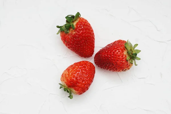 Tres fresas frescas sobre un fondo blanco bayas dulces de verano — Foto de Stock