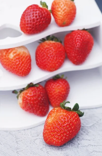 Montón de fresas maduras rojas frescas en el tablero de la caja blanca. Frutas frescas de verano. Aislado. Comida. Imagen vertical . — Foto de Stock
