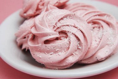 Pembe ev yapımı Marshmallows veya Zephyrin beyaz tabak. Pembe çilek çöl pembe bir arka plan üzerinde. Kopya alanı.
