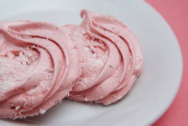 Pembe ev yapımı Marshmallows veya Zephyrin beyaz tabak. Pembe çilek çöl pembe bir arka plan üzerinde. Kopya alanı.