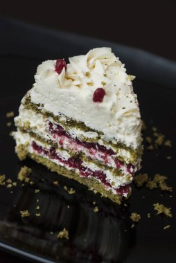 Siyah plaka üzerinde beyaz krem ve yeşil çay ile renkli Matcha Strawbery kek parçası. Benzersiz ev yapımı kek tarifi.