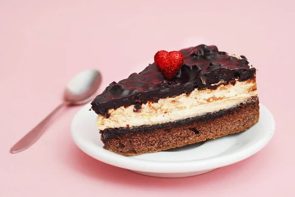 Nahaufnahme von Stück Schokoladenkuchen isoliert auf rosa Hintergrund mit Metalllöffel. Geburtstagstorte mit rotem Herz. — Stockfoto