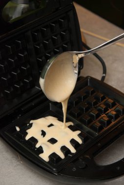 Pourring hamuru waffle evde pişirme için. Kahvaltı hazırlarken.