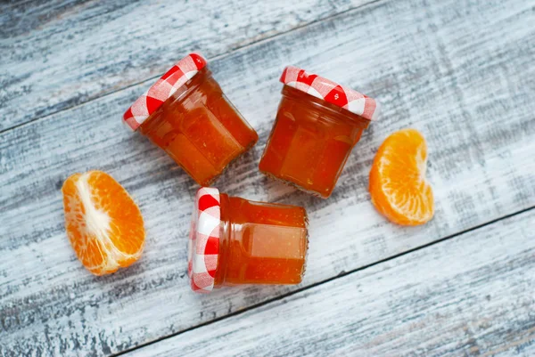 灰色の木製の背景にガラスの瓶にオレンジのジャム。フルーツは柑橘系の果物とジャムします。素朴な自家製の甘いジャム. — ストック写真
