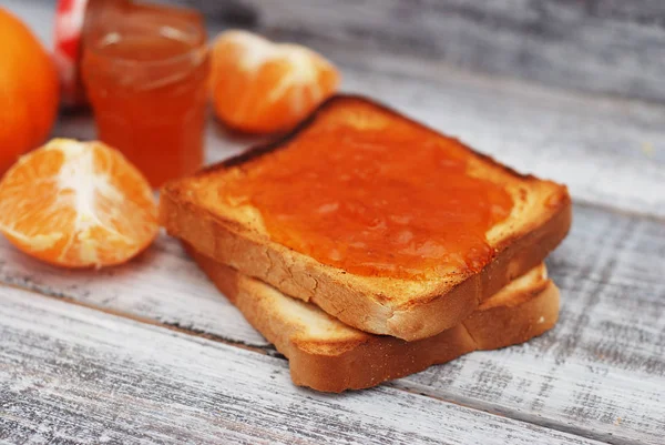 Färskt rostat bröd med hemmagjord apelsin stopp på grå plattan över trä bakgrund. — Stockfoto