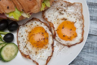 Sandwiche, Siyah Zeytin ve salatalık üstten görünüm yakın çekim rustik tarzı ahşap arka plan üzerinde kızarmış yumurta inwhite plaka. Sağlıklı yemek, Kahvaltı.