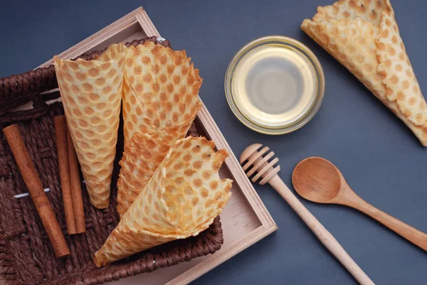 Conos de gofre vacíos Postres caseros con accesorios de madera y honney. Fondo azul. Vista superior — Foto de Stock