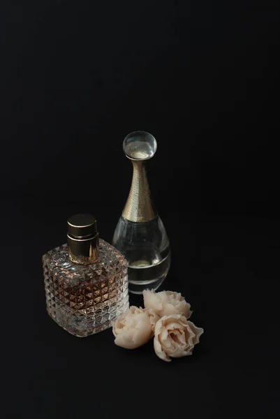 Perfume de garrafa e falsas rosas brancas no fundo preto escuro com cópia de texto espacial imagem vertical — Fotografia de Stock