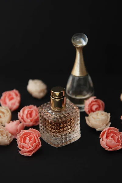 Flaschenparfüm und gefälschte Rosen auf dunkelschwarzem Hintergrund mit Kopierraum-Textansicht von oben — Stockfoto