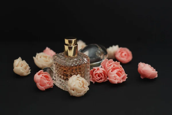 Flaschenparfüm und gefälschte Rosen auf dunkelschwarzem Hintergrund mit Leerzeichen-Text — Stockfoto