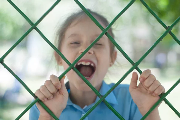 Sad Girl Behind the Bars. Sad Blured School girl behind Bars. Parenting, Education.