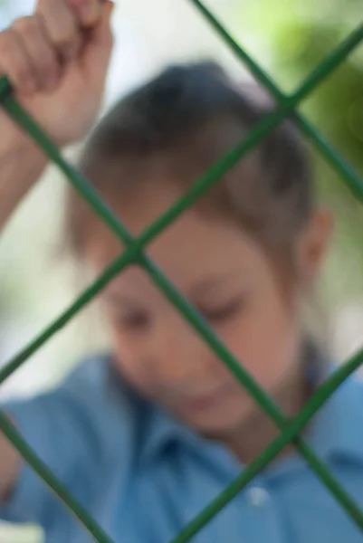 Girl Behind the Bars. Sad Blured School girl behind Bars. Parenting, Education.