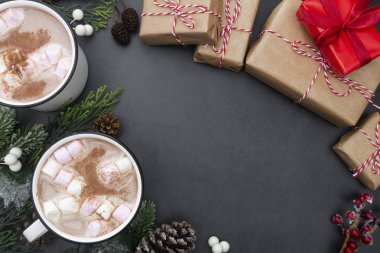 Marşmelovlu sıcak çikolata kupaları ve noel hediyesi kutuları. Köknar dallarıyla yatıyordu. Gri arka plan. Boşluğu kopyala.