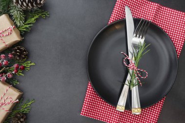 Noel 'de kurdeleli bir yer. Çatal ve bıçakla süslenmiş siyah tabak. Üst görünüm, alanı kopyala.