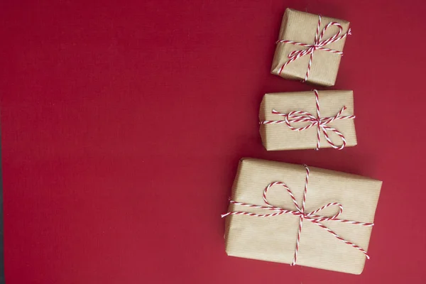 Řemeslné dárkové krabice přes červené pozadí. Vánoční maketa s kopírkou. zimní dovolená s dárky, výhled shora, byt ležel. — Stock fotografie