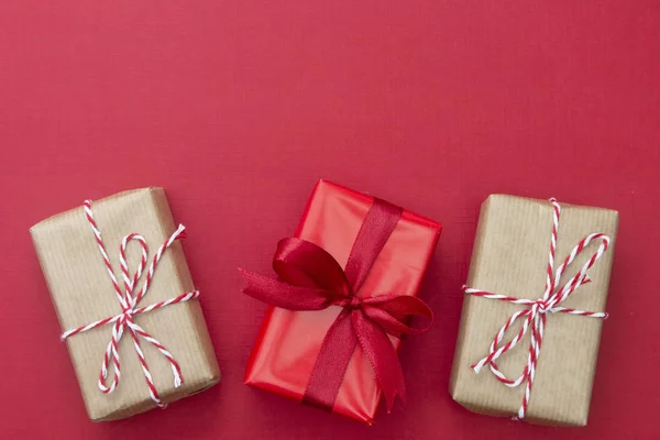 Vánoční červené pozadí, modelovat s řemeslné papírové dárkové krabice a kopírovat prostor. Zimní dovolená s dárky, výhled shora, byt ležel. — Stock fotografie