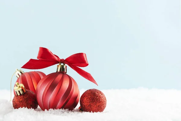 红色圣诞球装饰在雪地上，红色缎带与雪地隔离，蓝色背景。 冬季，圣诞贺卡，带有复制空间. — 图库照片