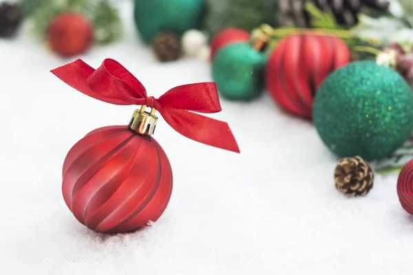 Bola de Navidad roja de cerca, adorno con cinta y ramas de abeto verde, conos de pino, sobre fondo de nieve blanca. Vacaciones de invierno. Tarjeta de felicitación abstracta de Navidad. Copiar espacio . — Foto de Stock