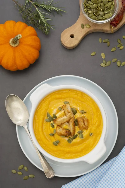 Pumpkin soup in a bowl,with fresh pumpkin seeds. Autumn foods. Healthy, vegetarian food, flat lay dark background.