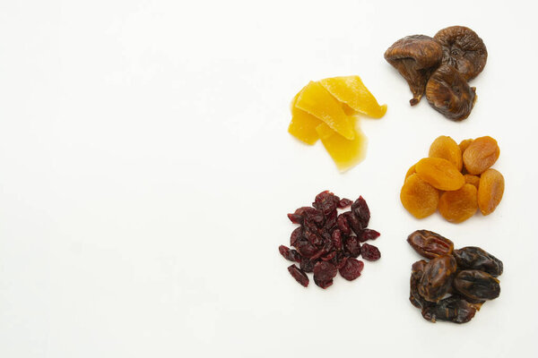 Mix of dried fruits heaps isolated on white background with copy space - figs, dates, mango, cranberries. Breakfast or snack, healthy food.