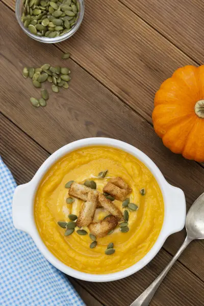 Pumpkin soup in a bowl,with fresh pumpkin seeds. Autumn foods. Healthy, vegetarian food, wooden background.
