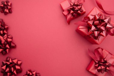 Kırmızı hediye kutuları ve kurdele yayları, kırmızı arka planda izole edilmiş, kırmızı yay ile. Üst Manzara. Uzayı kopyala Noel, Parti veya Valentin Günü konsepti.