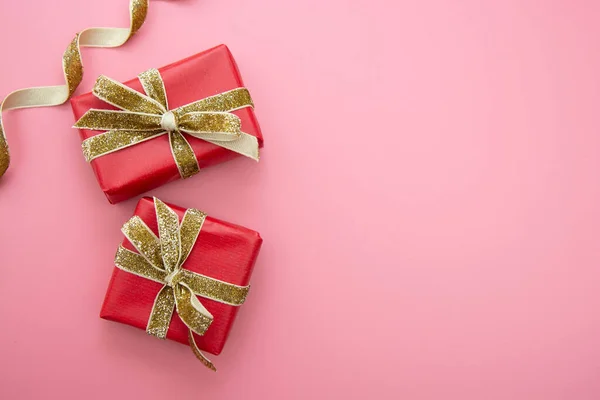 Röd presentask och gyllene båge, på rosa bakgrund. Alla hjärtans dag, födelsedag, fest koncept. — Stockfoto