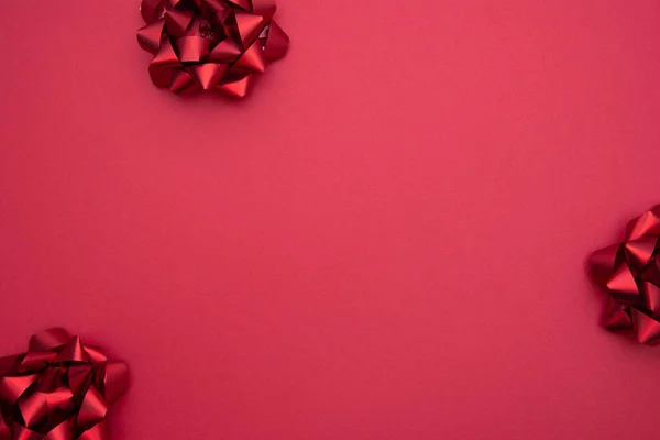 Czerwone wstążki kłaniają się na czerwonym tle, płaskie leżały. Impreza, urodziny, Boże Narodzenie lub Walentynki wzór. Układy płaskie. — Zdjęcie stockowe