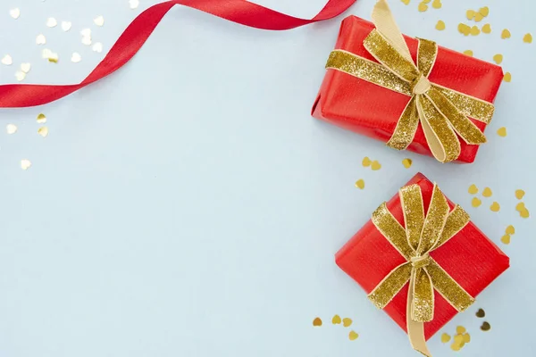 Ovanifrån av två röda presentaskar med gyllene glittrande band och gyllene konfetti. Alla hjärtans dag, jul eller födelsedag koncept. — Stockfoto