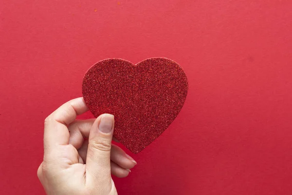 Fondo del Día de San Valentín. Mujer sosteniendo el corazón rojo sobre fondo rojo, vista superior con espacio para copiar . — Foto de Stock