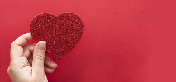 Vista superior de las manos femeninas que sostienen un corazón brillante brillante aislado sobre fondo plano, espacio de copia . — Foto de Stock