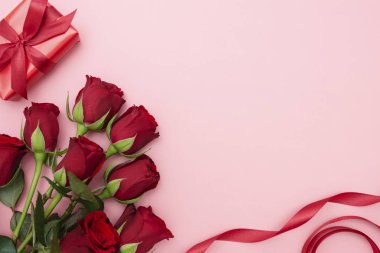 Sevgililer Günü, kırmızı güller ve kurdeleli hediye kutusu, kırmızı arka planda düz bir zemin, fotokopi alanı olan soyut doğum günü arkaplanı..