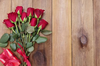 Kırmızı güller ve kurdeleli hediye kutusu, ahşap arka planda yatıyordu. Sevgililer Günü, kopyalama alanı olan soyut arkaplan.