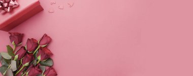 Sevgililer Günü, kırmızı güller ve kurdeleli hediye kutusu, kırmızı arka planda düz bir zemin, fotokopi alanı olan soyut doğum günü arkaplanı..