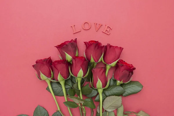 Rosas vermelhas e letras de amor inscrição, sobre fundo rosa flat lay. Dia dos Namorados, Aniversário fundo abstrato com espaço de cópia . — Fotografia de Stock