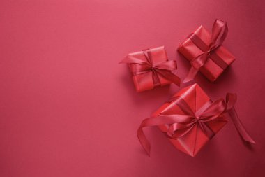 Kırmızı arka planda kırmızı fiyonklu kırmızı hediye kutuları. Üst Manzara. Uzayı kopyala Noel, Parti veya Valentin Günü konsepti.