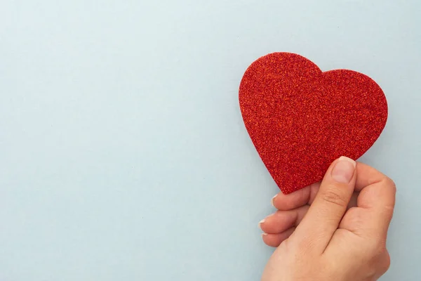 Valentine's Day background. Woman holding red heart on blue background, top view with copy space. Stock Image