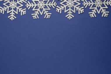 Mavi soyut Noel arkaplanı, gümüş kar taneleri kış süslemesi, mavi metin için yer kaplıyor..