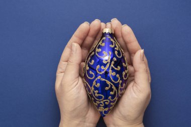 Noel ya da yeni yıl mavi arka planı, kadın eli ile dekoratif kış mücevherleri mavi arka planda, izole.