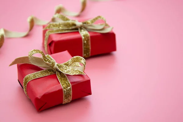 Röd presentask och gyllene båge, på rosa bakgrund. Alla hjärtans dag, födelsedag, fest koncept. — Stockfoto