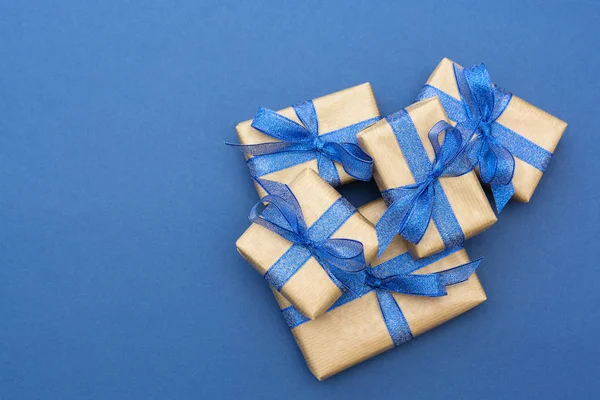 Vánoční nebo narozeninové dárky. Řemeslný papír zabalené dárkové krabice na modrém pozadí, byt ležel. — Stock fotografie