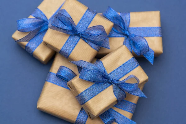 Vánoční nebo narozeninové dárky. Řemeslný papír zabalené dárkové krabice na modrém pozadí, byt ležel. — Stock fotografie