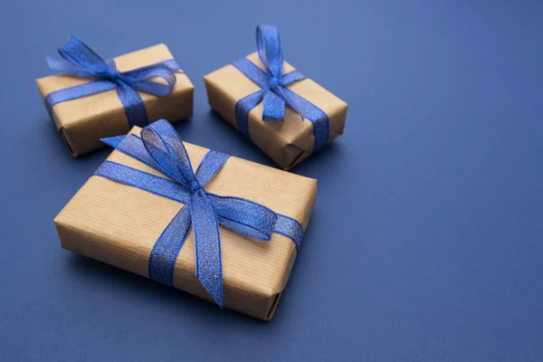 Vánoční nebo narozeninové dárky. Řemeslný papír zabalený v dárkových krabicích na modrém pozadí, plochý ležel. Kopírovat prostor. — Stock fotografie