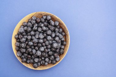 Mavi arka plan üzerinde ahşap kasede bir kase yaban mersini izole edilmiş. Taze meyve. Boşluğu kopyala.