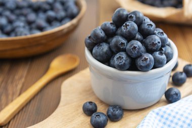 Tahta masadaki kasede olgun yaban mersini. Kahvaltı için taze böğürtlen.