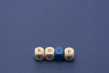 Aşk kelimesi mavi arka plandaki tahta bloklara yazılmış..